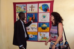 Schulleiter Jean-Damascene zeigt das Wandbild, das die Kinder aus Erzhütten 2012 für die Partnerschule gestaltet haben)